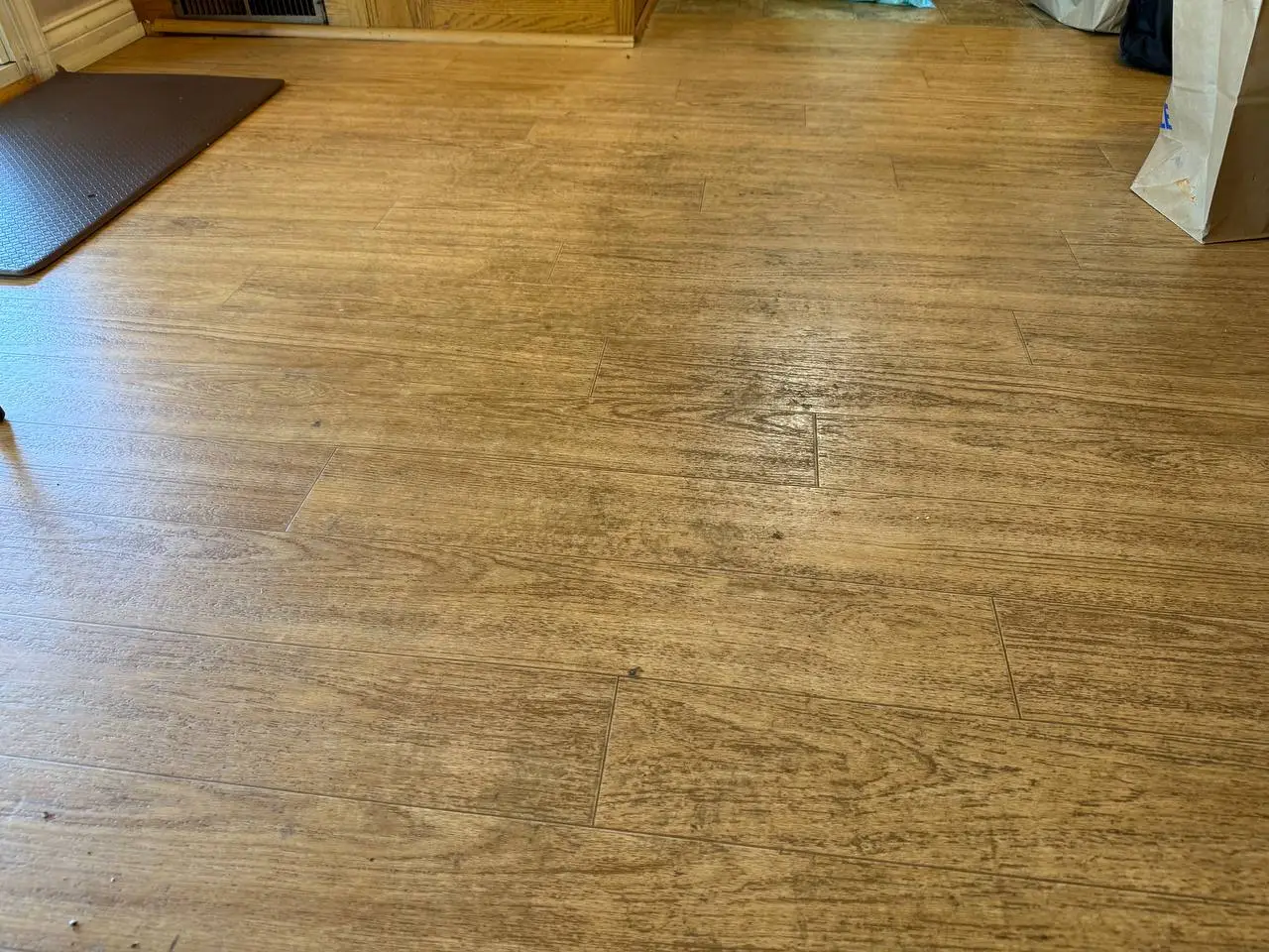 Kitchen floor before cleaning, with dark buildup across the surface.